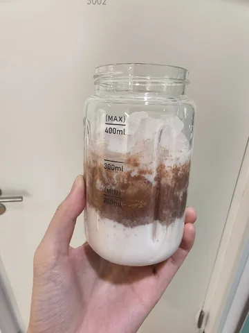 Glass coffee jar with label shot on a phone on a kitchen counter in warm indoor light