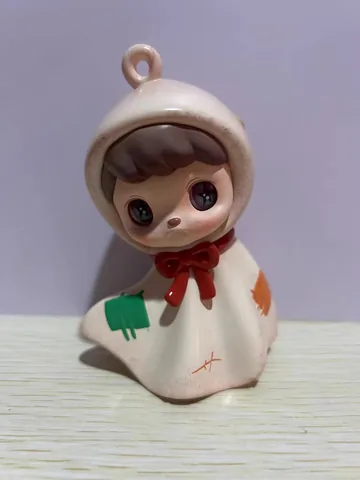 A vinyl art toy shot on a phone, on a wooden surface against a purple wall in warm light