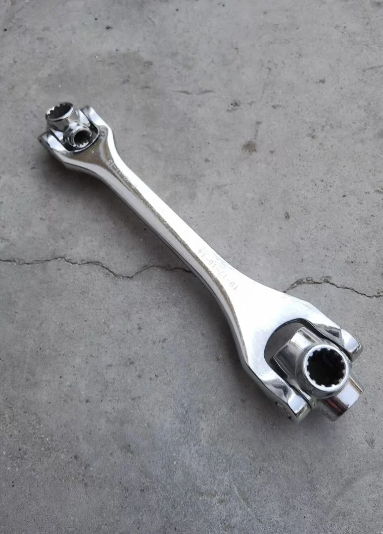 Chrome multi-socket wrench shot on a phone on a concrete floor with hard shadows and scattered reflections